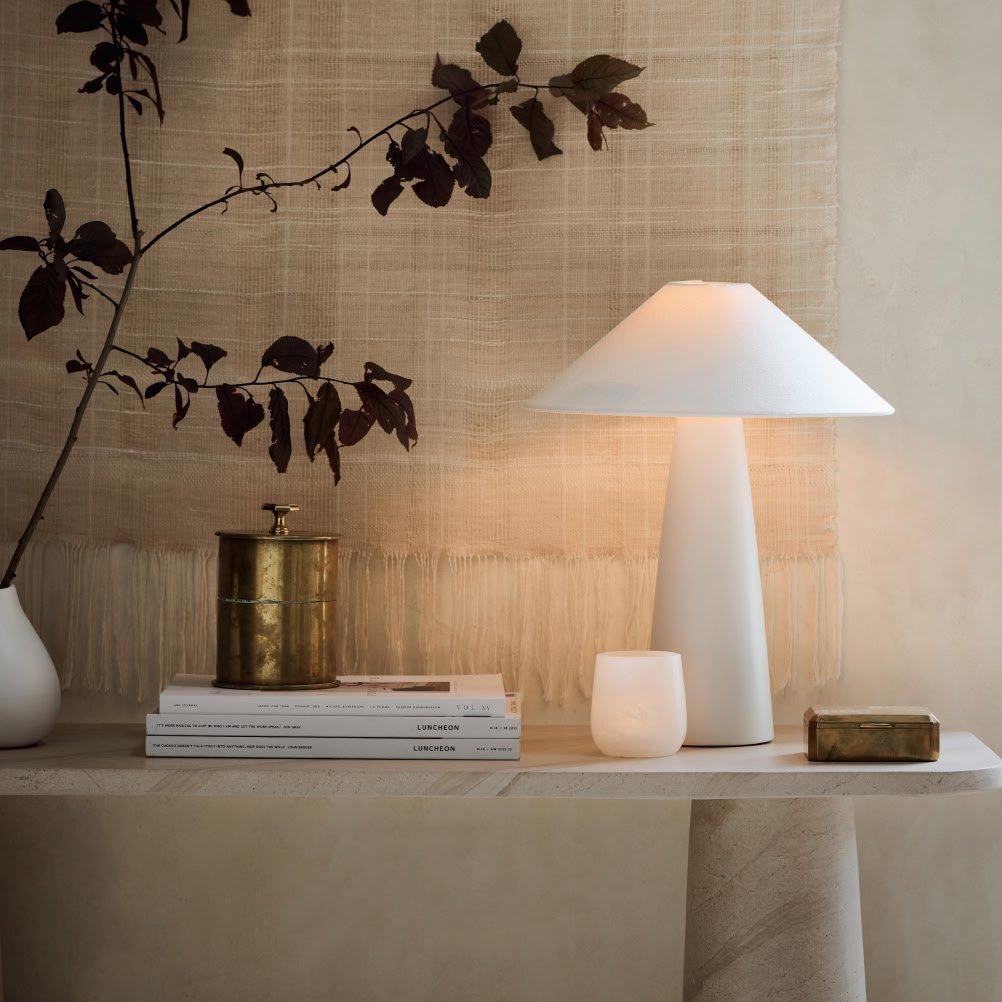 a table with a lamp, books, and a vase on it