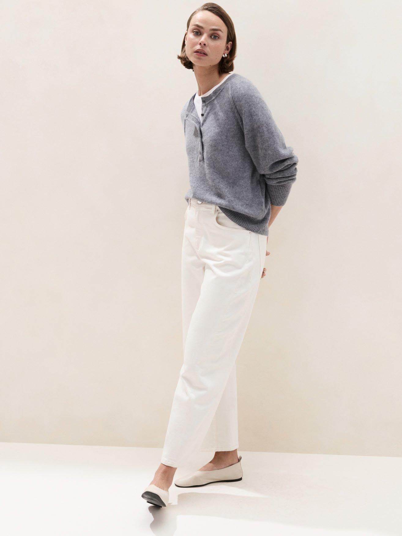a woman in white pants and a grey sweater