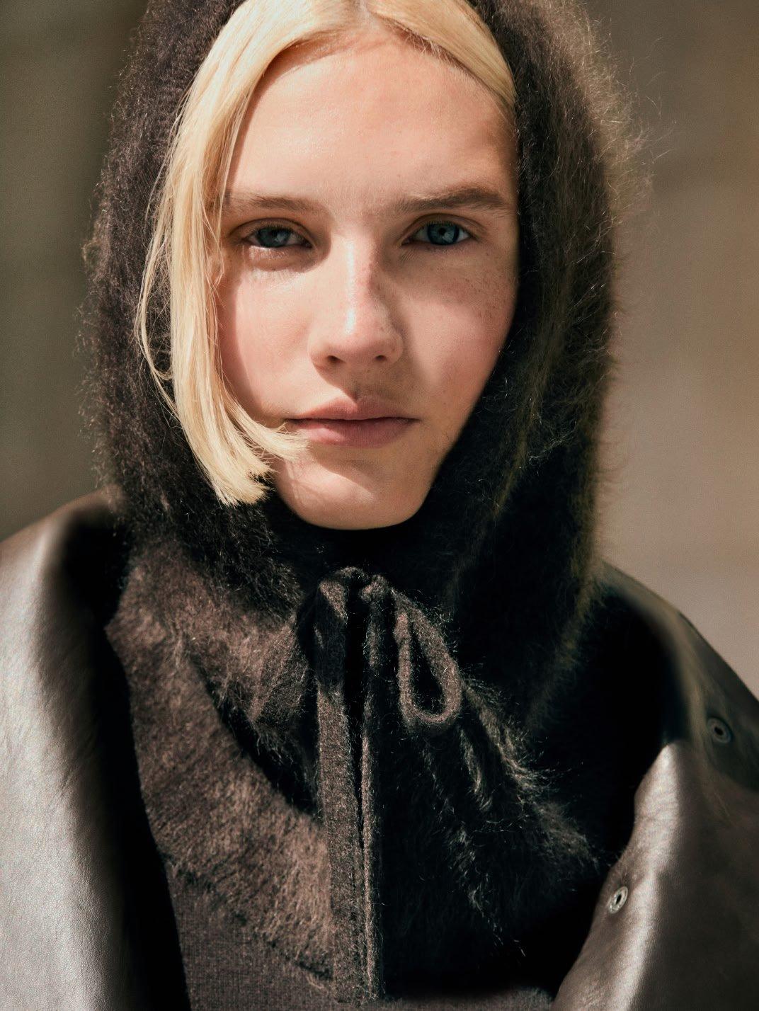 a woman with a hood on her head and a black jacket