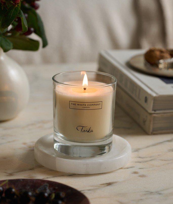 a candle sitting on a marble table next to a bowl of grapes