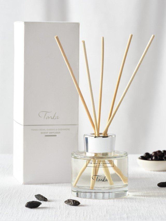 a reed diffuser with a box of black seeds next to it