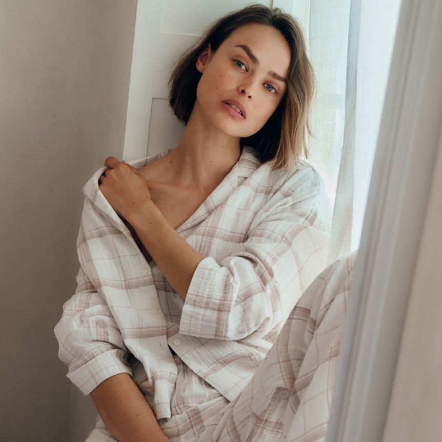 a woman in pajamas leaning against a window sill