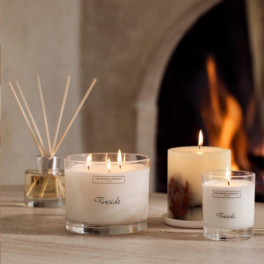 three candles sit on a table next to a fireplace