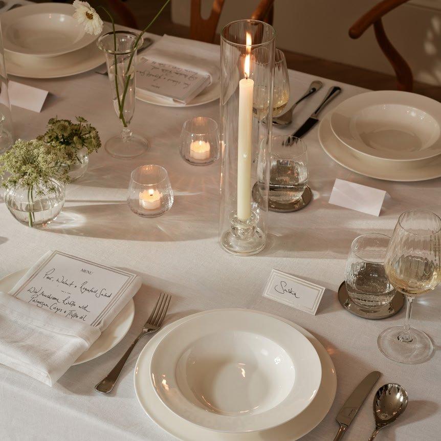 a table set for a dinner party with candles and place settings