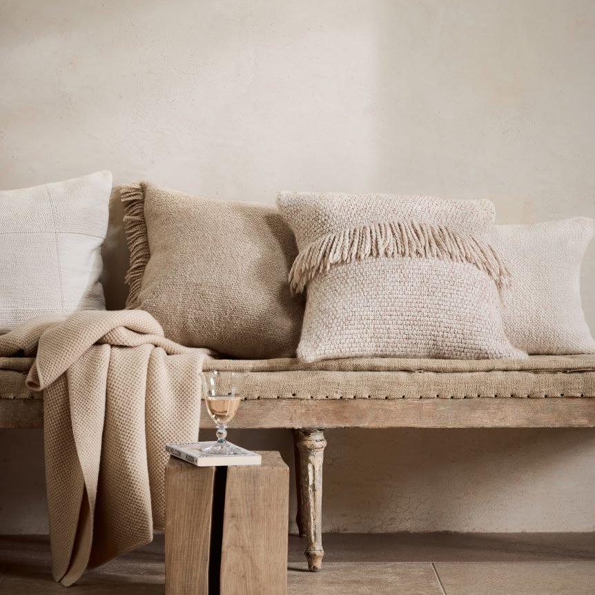 a bench with pillows and blankets on it in a room