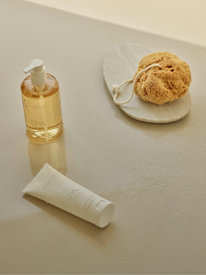 a white counter top with a sponge, soap, and a bottle of lotion