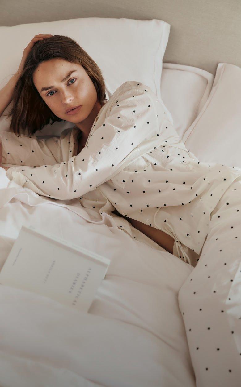 a woman in pajamas laying on a bed with a book
