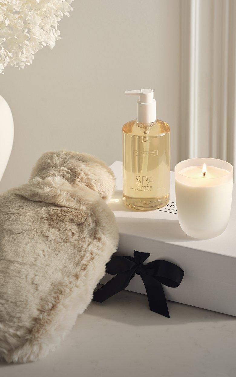a white candle, a bottle of lotion and a small bottle of perfume