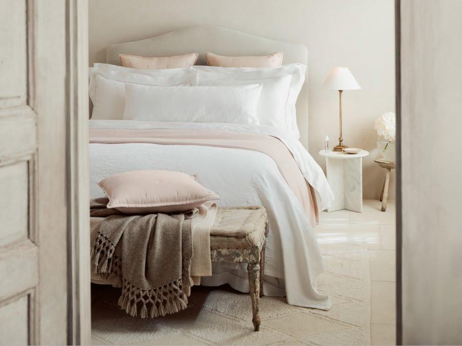a bed with a white comforter and pillows in a bedroom